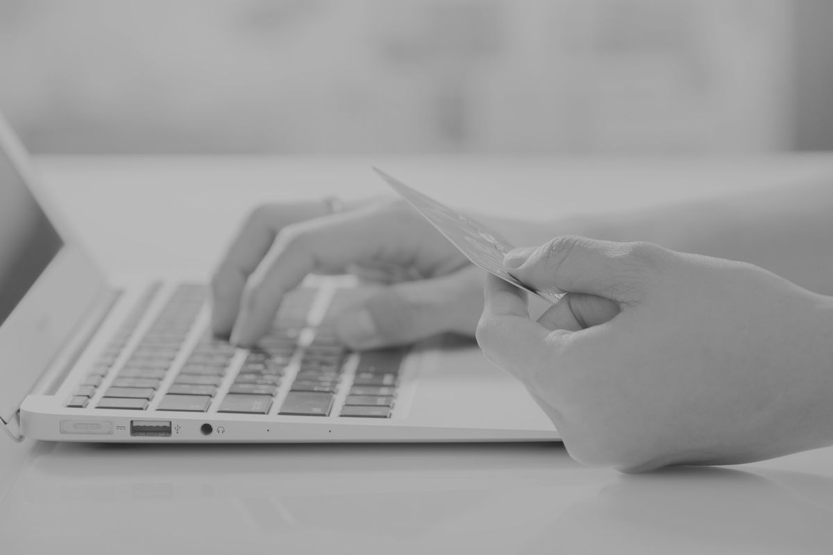 A person reviewing a payment card beside a laptop